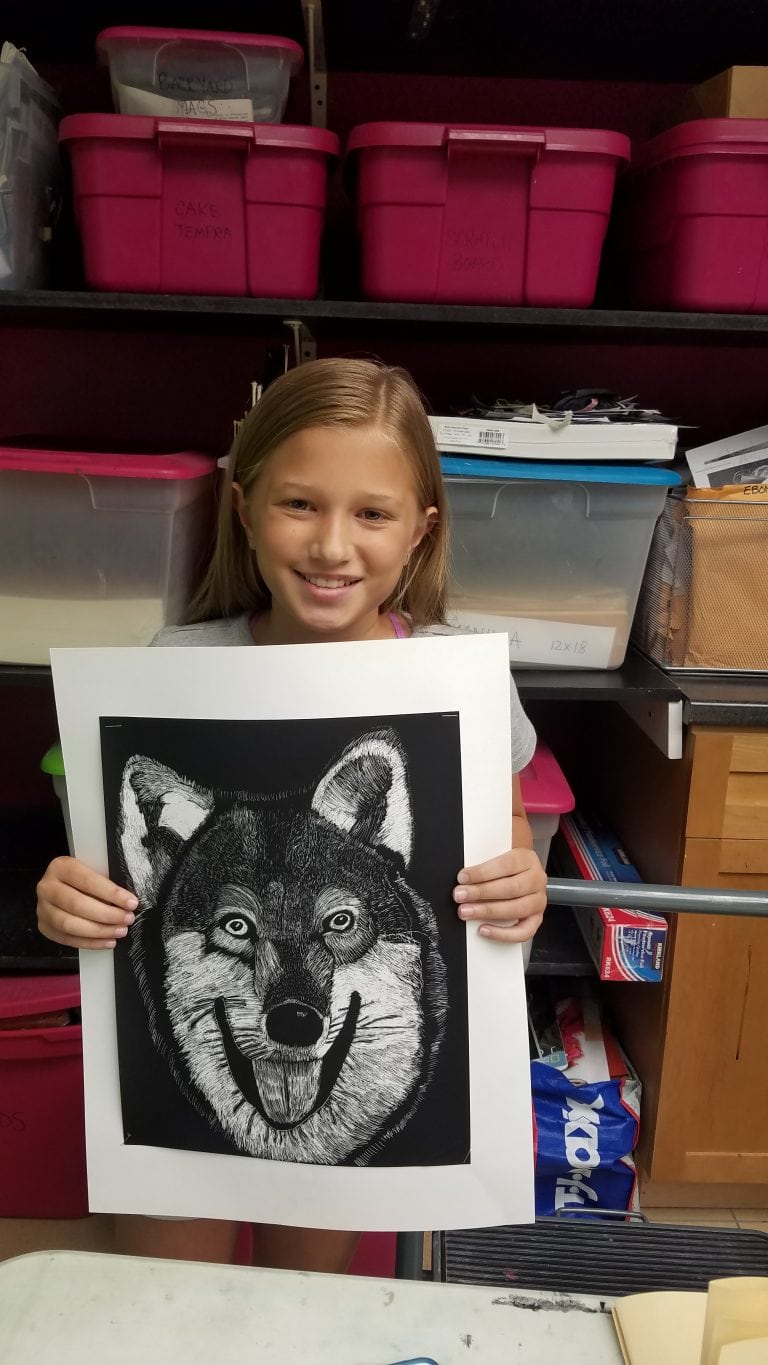 Young girl holding black and white drawing of husky dog