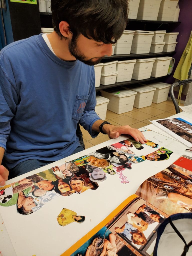 male student with brown hair and beard wearing a long sleeve shirt working on photo montage