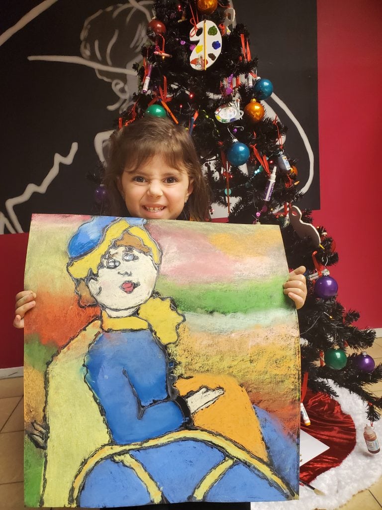 Young girl holding charcoal drawing of a women in blue and yellow sitting in a chair
