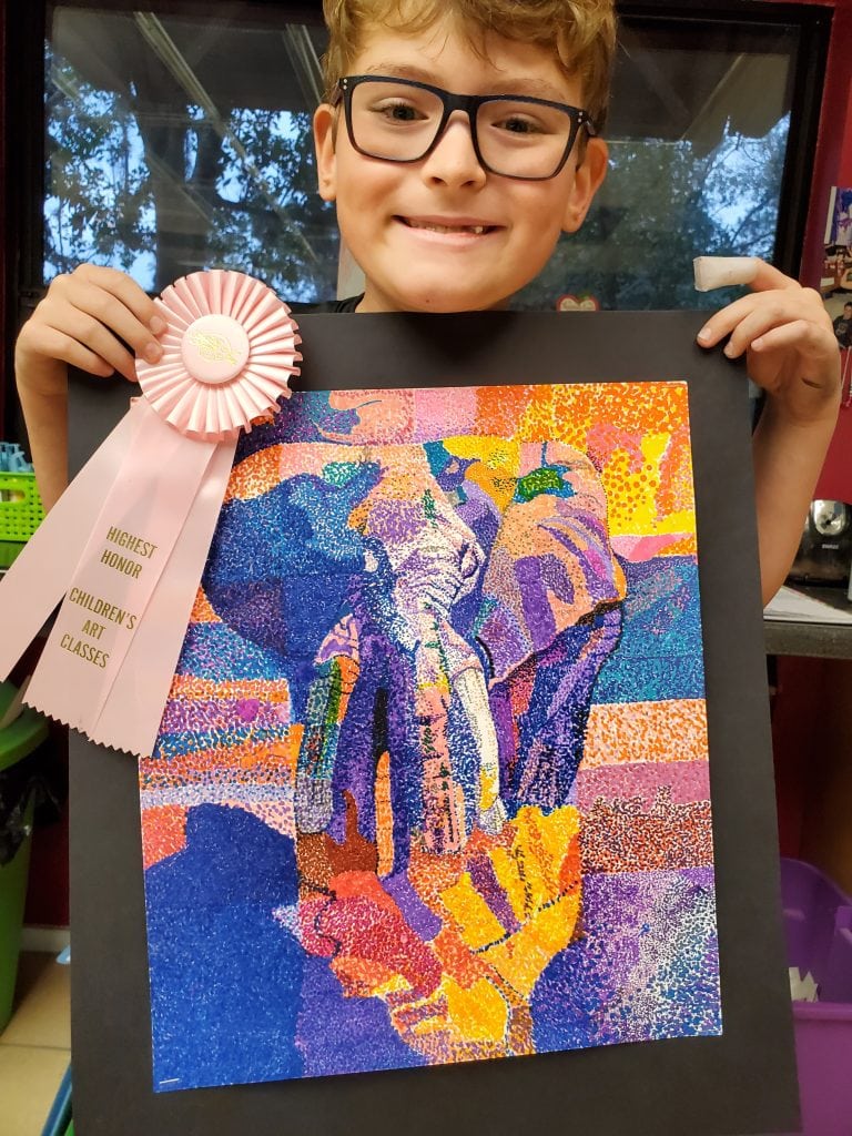 Young boy holding a colorful stippling of an elephant with a pink ribbon award