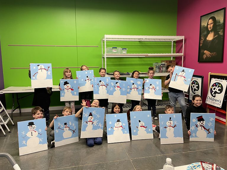 group of children holding acrylic paintings of snowmen