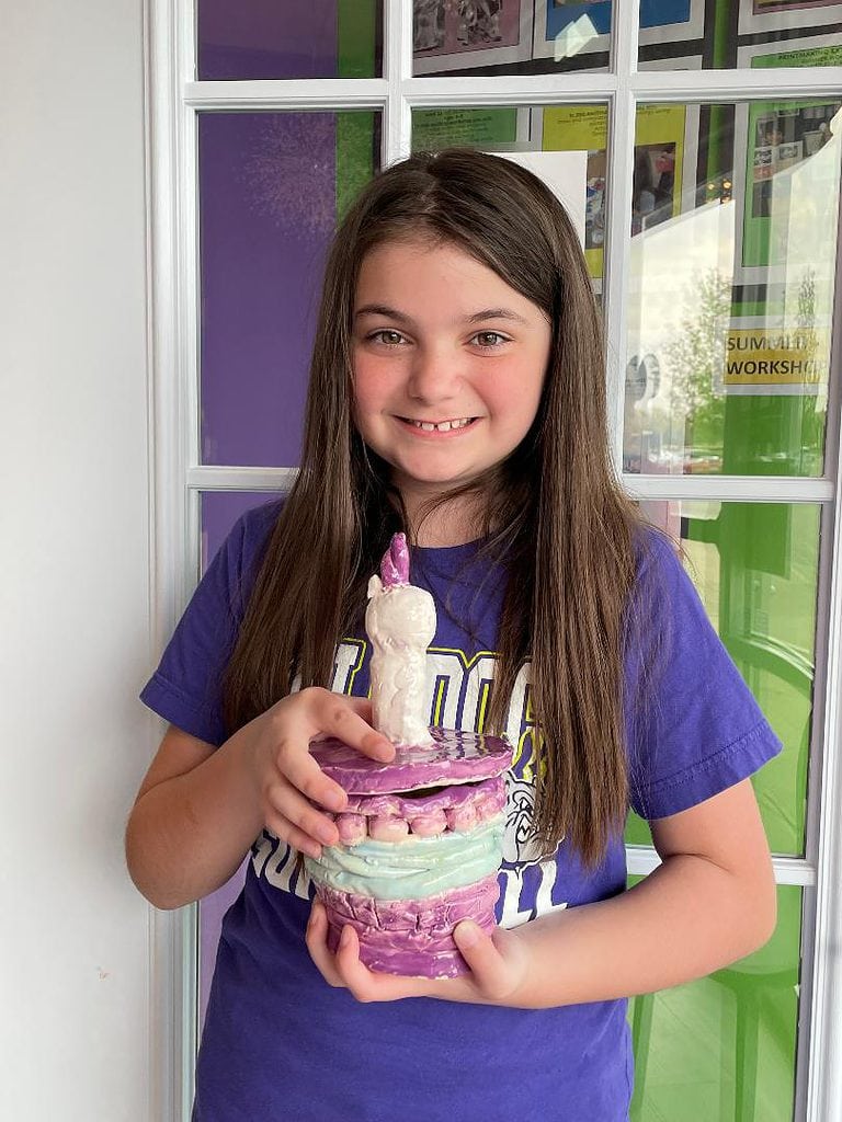 Girl with brown hair in a purple shirt holding a ceramic coil pot unicorn