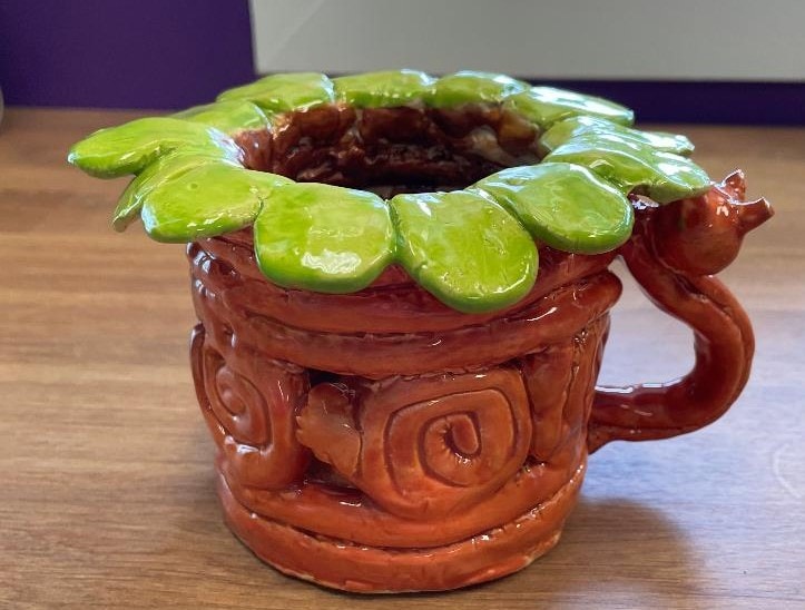 brown ceramic coil pot with green petal rim