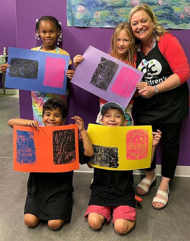 group of 4 children holding their printmaking projects
