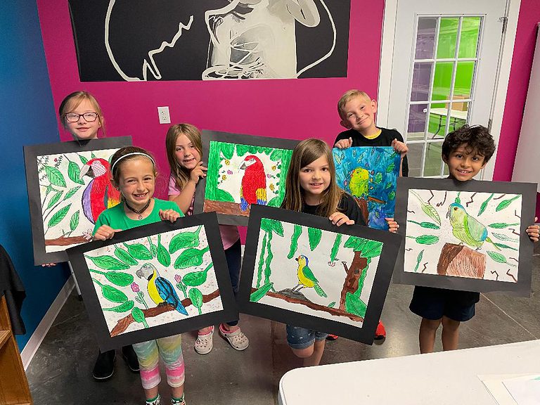 group of children holding their tropical birds paintings