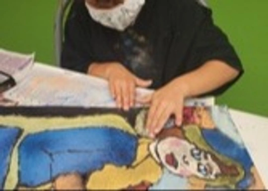 Student using hands to spread pastel glue